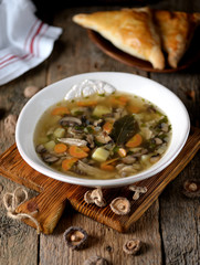 Mushroom soup with potatoes, carrots, onions and chicken meat on an old wooden background. Rustic style.