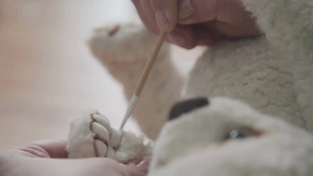 Handmade toy. Fine brush for drawing: paws of a soft toy. Teddy bear in vintage style: the process of creation. The master draws the dividers on the foot for a teddy bear in an old-fashioned style.