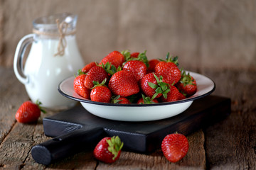 Fresh juicy organic strawberry with milk on an old wooden background. Rustic style.