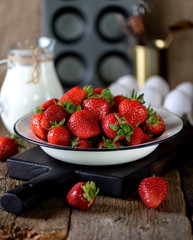 Fresh juicy organic strawberry with milk on an old wooden background. Rustic style.