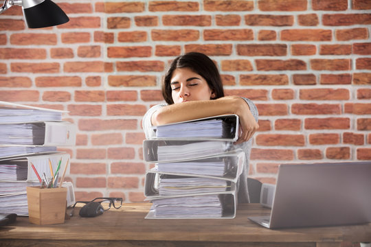 Businesswoman Sleeping On Folder Stacked In Office