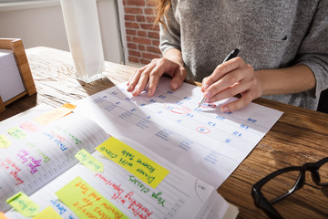 Businesswoman Marking Schedule On Calendar