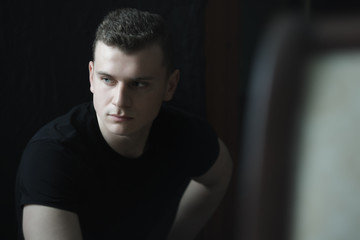 Studio dark portrait of young man with short brown hair in low-key lighting