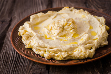 Plate of creamy hummus on wooden table.Ramadan food. Selective focus. Toned image