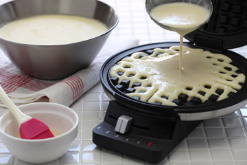 preparing homemade waffles by waffle maker machine.