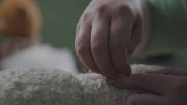 Sew a soft toy: the seam on the back. Female hands sew a teddy bear in an old-fashioned style. Concept: a favorite toy of children is a teddy bear. Needle and thread in the hand of a woman