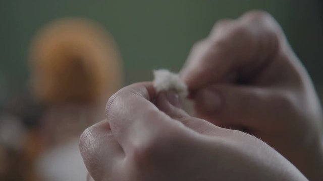 Stitching the details of a plush toy. Women's hands sew a teddy bear. Sew a soft toy: the seam on the back. Female hands sew a teddy bear in an old-fashioned style. Sewing the head of a plush toy.