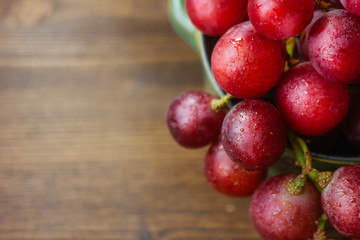 bunch of grapes on ceramic bowl over the wooden background