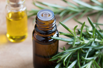 A bottle of rosemary essential oil with fresh rosemary twigs