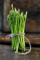 Hip of asparagus standing on wooden board.