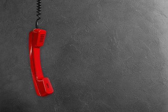 Handset from landline red phone on a gray wall background