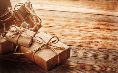 Gift box in kraft paper with bow on wooden background