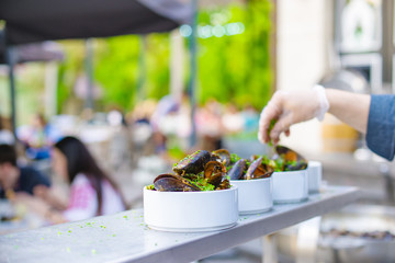 A portion of cooked mussels on a plate. Outdoor food on the terrace.