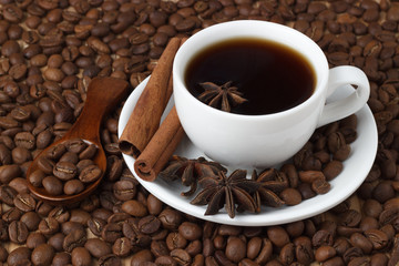Coffee in a cup with cinnamon sticks on the background of coffee beans