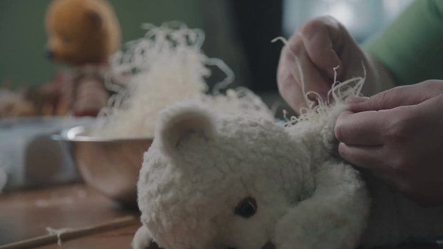 The process of stuffing a soft toy filler. Filler for soft toys. The process of creating a soft handmade toy. Work details: craft toy in the old-fashioned style. Beige teddy bear