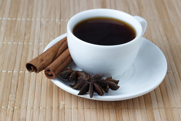 Coffee in a white cup with anise and cinnamon sticks