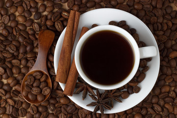 Coffee in a cup with cinnamon sticks on the background of coffee beans