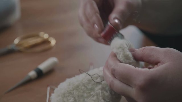 Teddy bear: the process of creation. Craft production. Details and elements of a soft plush toy: female hands sew parts of a toy. Handmade. A rare collectible toy is a teddy bear.
