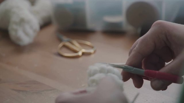 Wdoing a teddy bear. The concept of exclusive work. Craft production. Details and elements of a soft plush toy: female hands sew parts of a toy. Handmade. Favorite toy of children is a teddy bear.