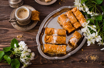 Homemade baklava rolls in iron try on wooden background. Ramadan food. Selective focus
