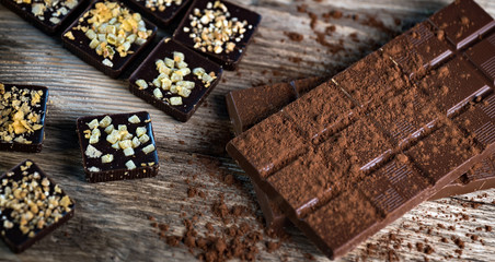 Chocolate bar pieces with cocoa powder.  Background with chocolate. Slices of chocolate,  Copyspace