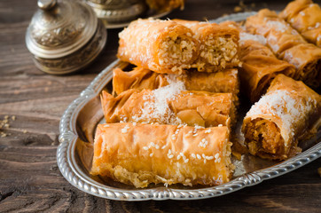 Homemade baklava rolls in iron try on wooden background. Ramadan food. Selective focus