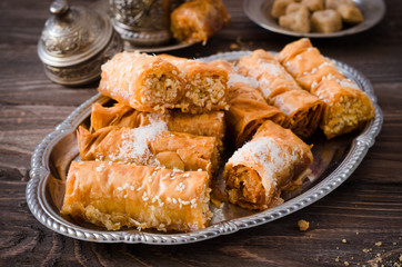 Homemade baklava rolls in iron try on wooden background. Ramadan food. Selective focus