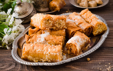 Homemade baklava rolls in iron try on wooden background. Ramadan food. Selective focus