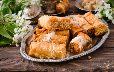 Homemade baklava rolls in iron try on wooden background. Ramadan food. Selective focus