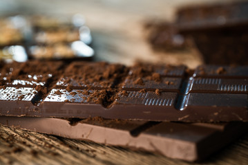 Chocolate bar pieces with cocoa powder.  Background with chocolate. Slices of chocolate,  Copyspace