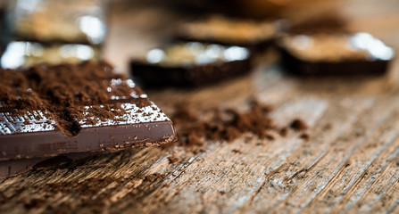 Chocolate bar pieces with cocoa powder.  Background with chocolate. Slices of chocolate,  Copyspace