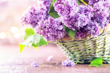 Lilac flowers bunch in a basket over blurred wood background