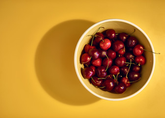 Red Cherries in a Bowl on the Yellow Background