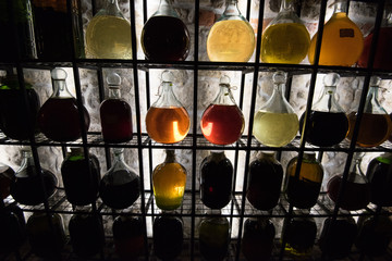 Alcohol in vintage large bottles is placed on decorative racks with vibrant illumination..