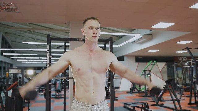 A man is training with dumbbells in the gym