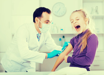 Fototapeta premium Male doctor injecting little patient