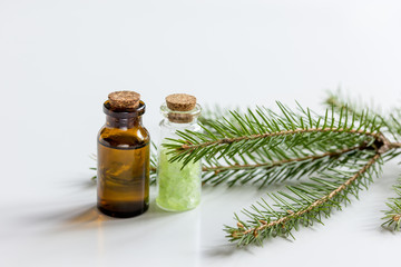 Spruce needle aromatherapy essential oils and salt in bottles on white table background