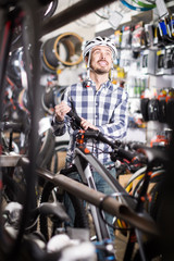 Fototapeta na wymiar joyous man in helmet chooses for himself sports bike in bicycle shop
