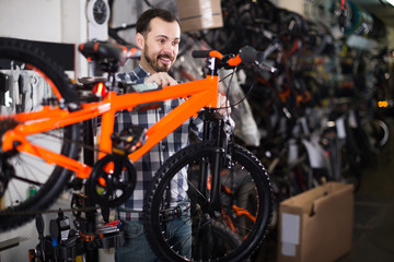 Obraz na płótnie Canvas Man in sports workshop mounts bike using special tools
