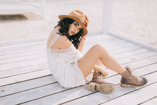 Beautiful model in hat and dress in hippie style posing on summer beach.