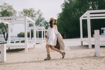 Beautiful model in hat and dress in hippie style posing on summer beach.