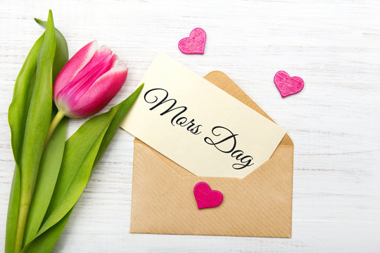Mother's day card with Swedish words: Mother's day. Tulip  and envelope on white wooden background