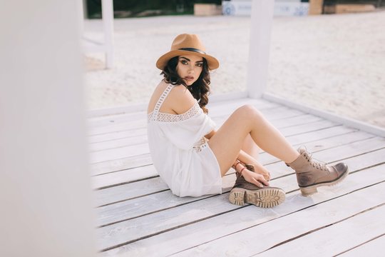 Beautiful model in hat and dress in hippie style posing on summer beach.