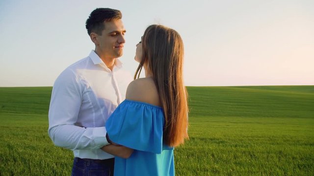 Couple in love stands in embraces, looking and kissing each other on the horizon