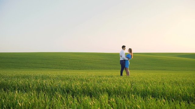 Couple in love stands in embraces, looking and kissing each other on the horizon