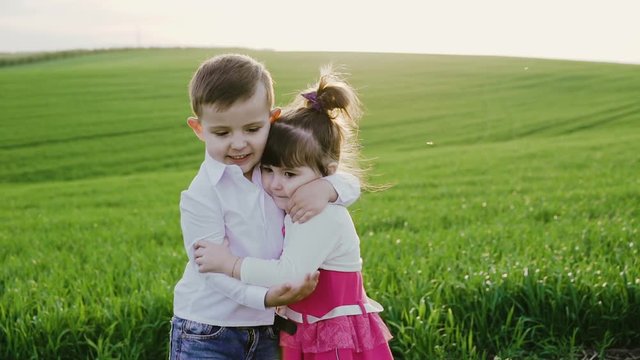 Little couple in love embracing each other on the spring wheat field on sunset