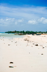 Tropical white sand beach with green palm trees and parked fishing boats in the sand. Exotic island paradise
