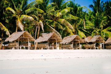Landscape of paradise tropical island with palms, cottages and white sand beach
