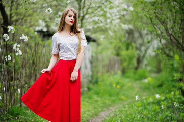 Portrait of beautiful girl with red lips at spring blossom garden, wear on red dress and white blouse.