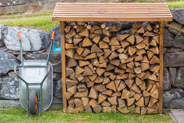 Wheelbarrow and a open shed shelter with burning fire wood with natural stones and grass on the background